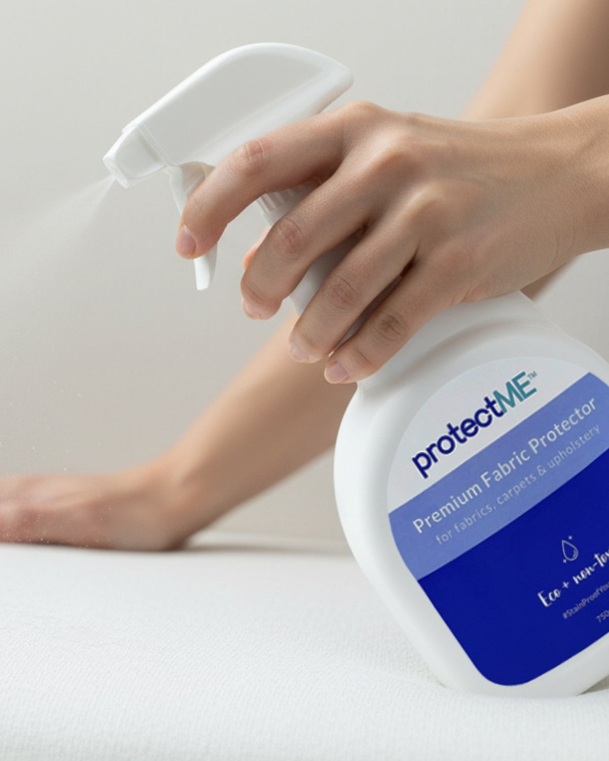 Person using a 'protectME' a non-toxic fabric protector on a fabric surface.